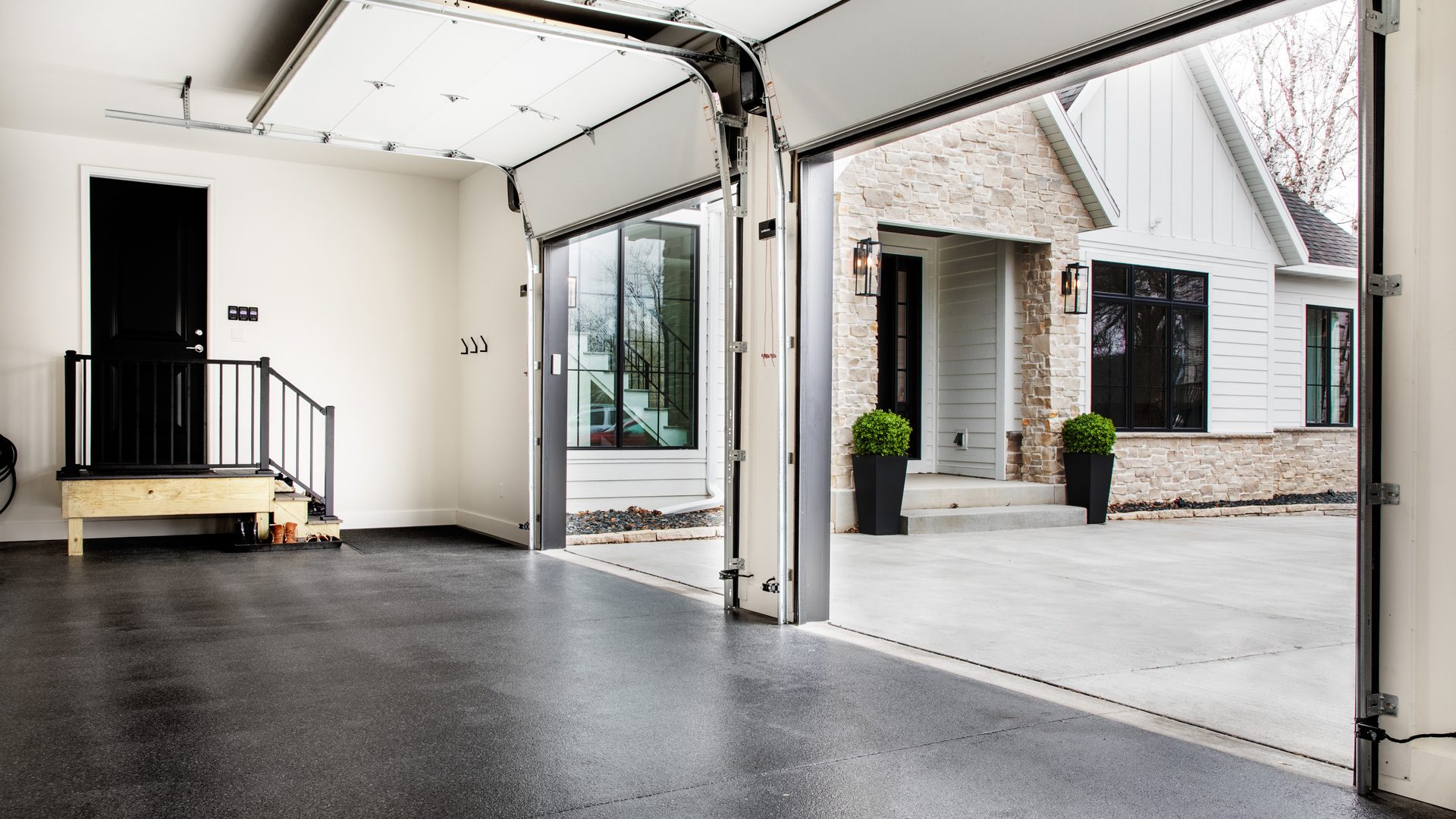 Open residential garage with a dark floor coating